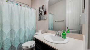 A bathroom with a white sink, a mirror, a toilet, and a shower curtain with a leaf pattern. - MODERN NEWER HOME CLOSE TO NAPA WINE COUNTRY, SACRAMENTO &  SAN FRANCISCO (FAIRFIELD)