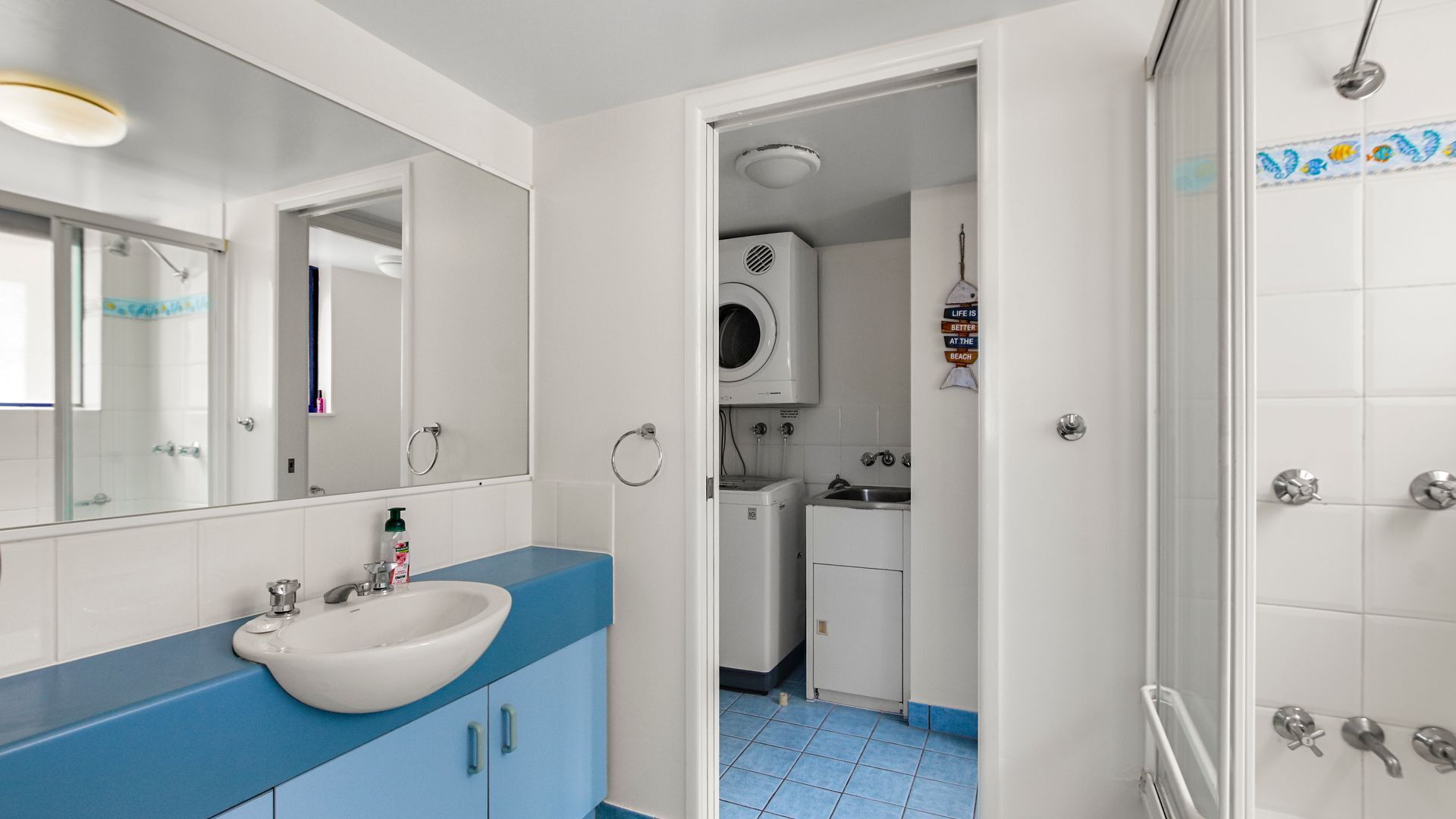 Baño con lavamanos, espejo y zona de ducha.
