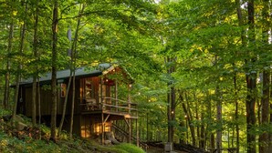 A wooden cabin with a balcony, surrounded by a forest. - WiFi l Heat/AC l Firepit/Grill-- Glamp in Style! (Riverton)