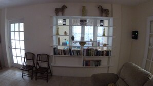 A living room with a bookshelf, two chairs, a sofa, and a door with a window.