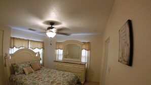 A bedroom with a bed, dresser, and ceiling fan.