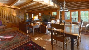 A spacious wooden cabin with a dining area, kitchen, and a staircase leading to an upper level.