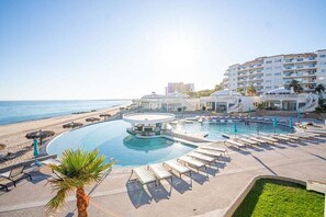 Um resort com piscina, espreguiçadeiras e vista para a praia.