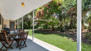 An outdoor patio with a table and chairs, surrounded by lush greenery and trees.