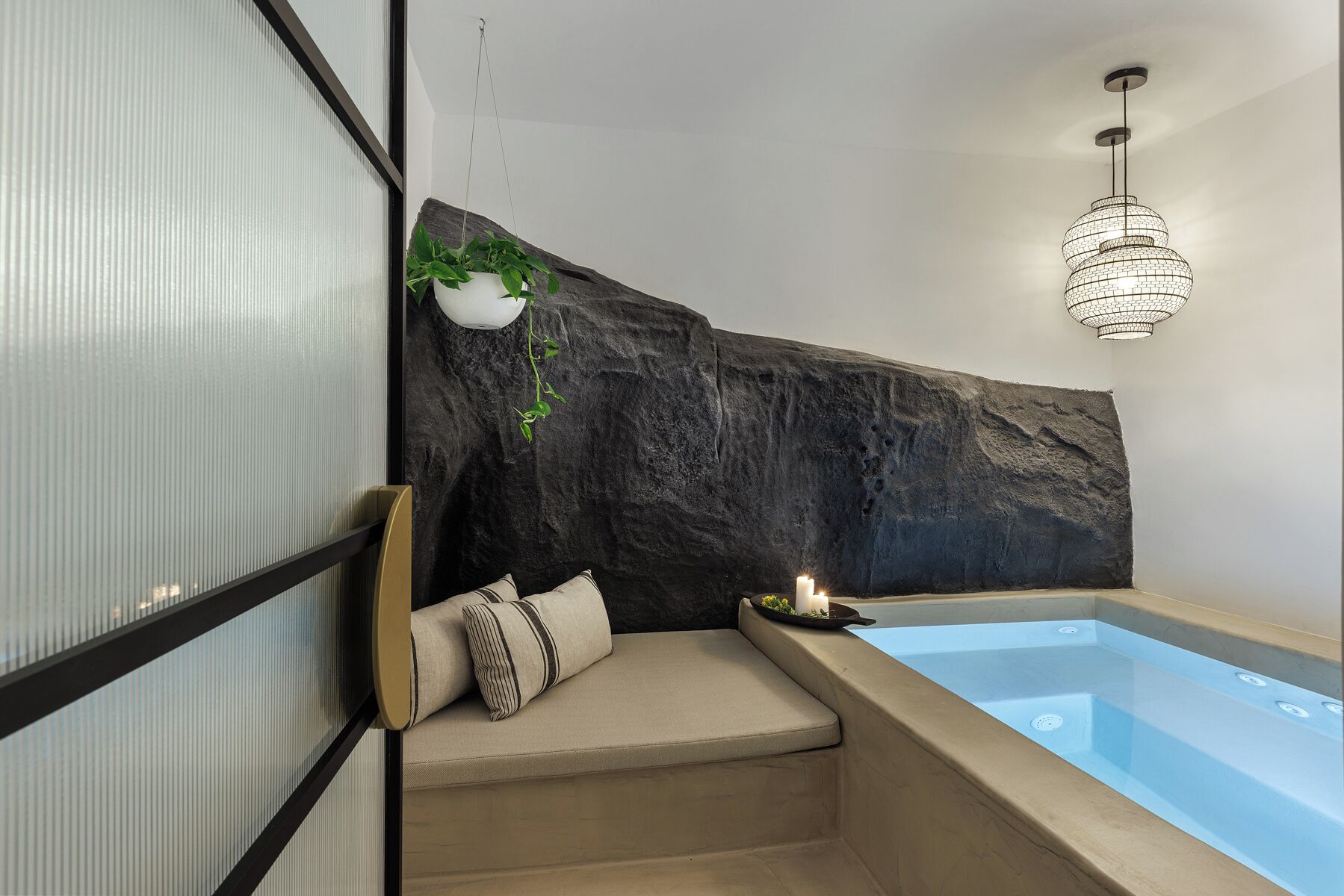 A modern bathroom with a large bathtub, a hanging plant, and a unique wall design.