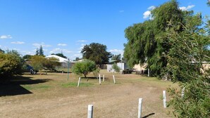 A rural property with a fenced yard, a small building, and a car parked nearby.