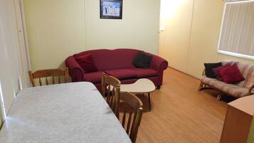 A living room with a red sofa, a wooden dining table, and a striped sofa.