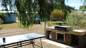 A backyard with a barbecue grill, a picnic table, and a parked car.
