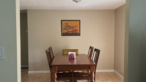 Un coin repas avec une table et des chaises en bois, un tableau au mur et un luminaire au plafond.