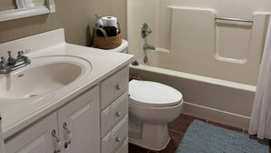 Une salle de bain équipée d’un lavabo, de toilettes, d’une baignoire et d’un rideau de douche.
