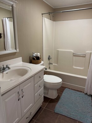 Een badkamer met een wastafel, toilet, bad en douchegordijn.
