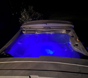 Een hottub met blauwe verlichting, gelegen in een donkere omgeving.