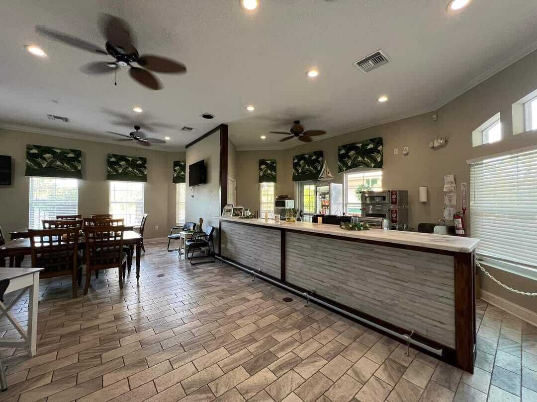 A spacious kitchen with a long counter, ceiling fans, and a dining area with wooden chairs.
