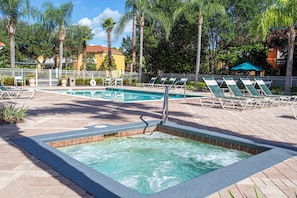 A pool area with a hot tub, lounge chairs, and a tiled deck. - Your perfect stay starts here. Near Disney/Universal. (Kissimmee)