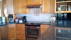 A kitchen with wooden cabinets, a stainless steel oven, a microwave, and a granite countertop. - Anderson Lake House  (Hot Springs)