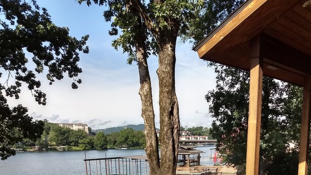 A wooden deck with a railing overlooking a lake, dock, and a gazebo. - Anderson Lake House  (Hot Springs)