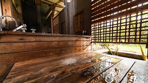 A wooden bench area with a water feature, wooden beams, and a view of the outdoors.