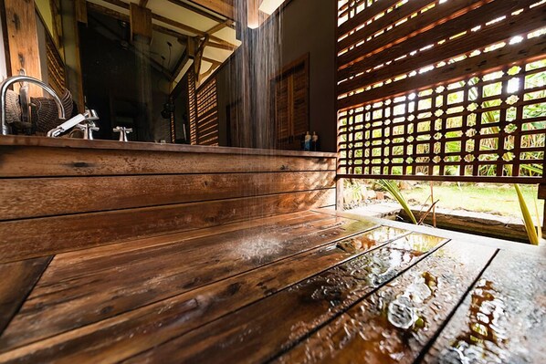 A wooden bench area with a water feature, wooden beams, and a view of the outdoors.