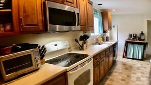 Una cocina con armarios de madera, microondas, estufa y lavabo.