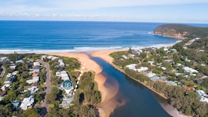 Vista aérea de una zona residencial costera con casas, una playa y un río.