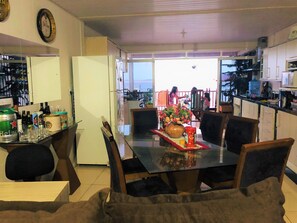 Un espace repas avec une table en verre, des chaises et une vue sur l’extérieur.