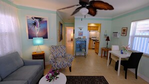 A living room with a sofa, patterned armchair, dining table, and ceiling fan. - Located steps from the ocean, offering true beach living (Hollywood)