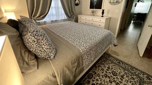A bedroom with a bed, a dresser, a mirror, and a door leading to another room. - Located steps from the ocean, offering true beach living (Hollywood)