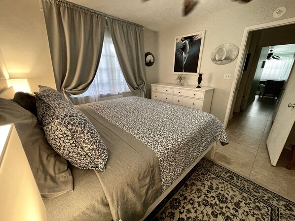 A bedroom with a bed, a dresser, a mirror, and a door leading to another room. - Located steps from the ocean, offering true beach living (Hollywood)