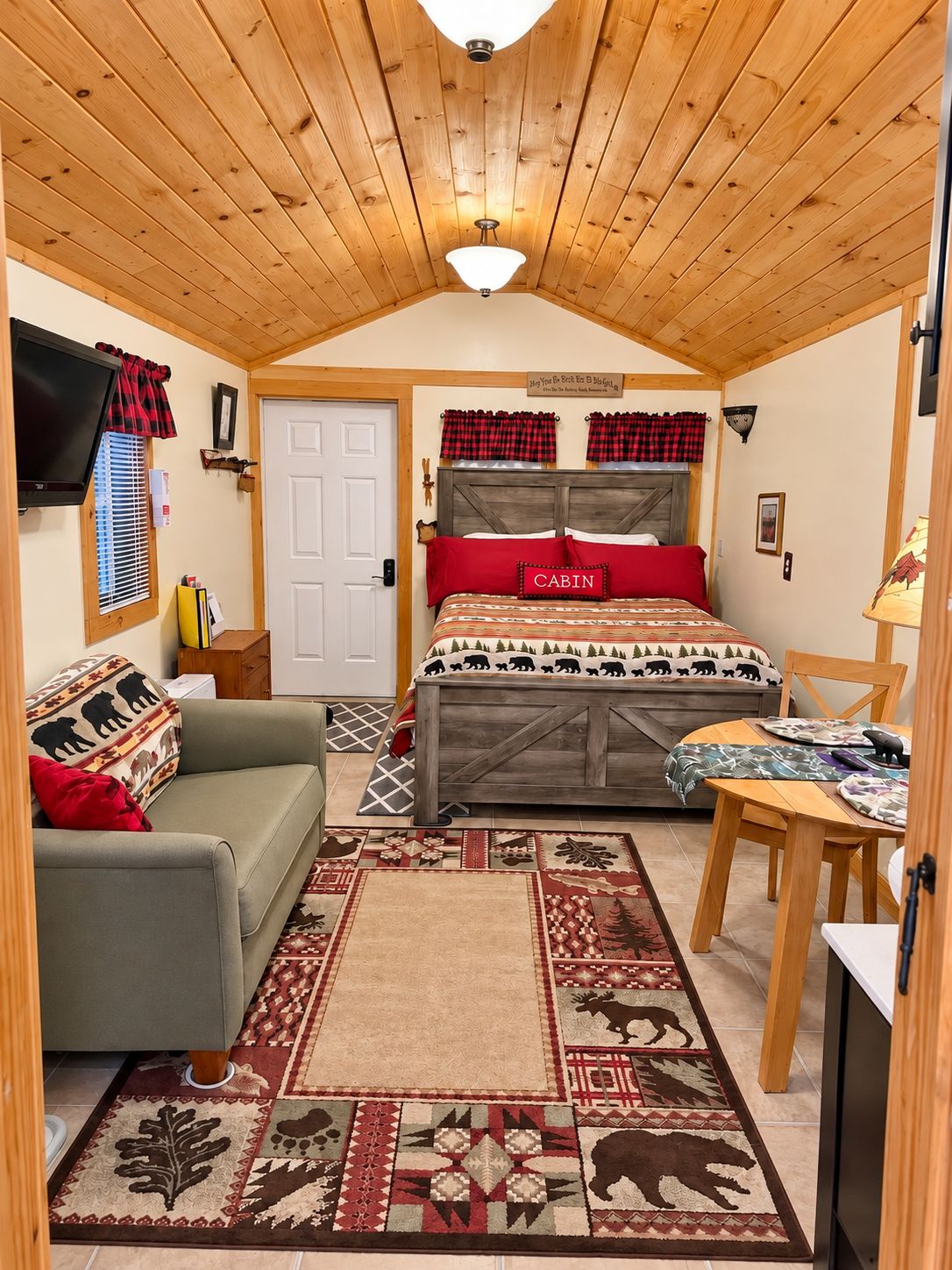 Une chambre confortable, aménagée dans le style d’un chalet, avec un lit, un canapé, une table à manger et un téléviseur.