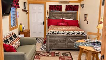Une chambre confortable, aménagée dans le style d’un chalet, avec un lit, un canapé, une table à manger et un téléviseur.