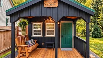 Une cabane avec une véranda, un banc, une table et une porte verte.