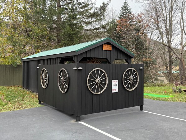 A cabin with a green roof, labeled 'Cabin' and 'Cutest Cabin,' surrounded by a wooden fence with large wheels. - Cutest Cabin in Windham 1 minute to ski slope & town - BBQ  Grill  & Fire Pit  (Windham)