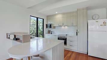 A modern kitchen with a central island, wooden cabinets, a built-in oven, and a refrigerator.