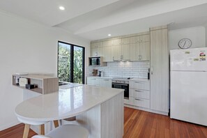 Une cuisine moderne dotée d’un îlot central, de meubles en bois, d’un four encastré et d’un réfrigérateur.