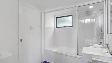 A modern bathroom with a glass-enclosed shower, a white bathtub, and a sink with a countertop.