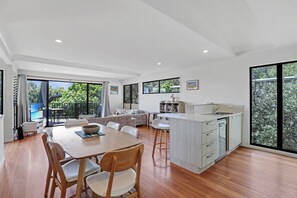 Une cuisine moderne avec un coin repas, de grandes fenêtres et une vue sur la verdure.