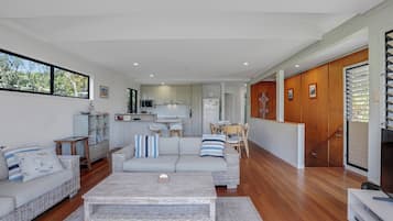 A modern living room with a sofa, coffee table, and a dining area with chairs.