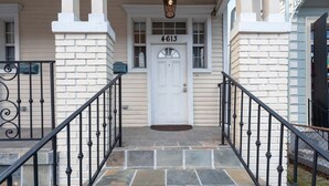 A front entrance with a white door, stone steps, and black iron railings. - Updated Quiet and Comfortable Uptown 1br Apt (New Orleans)