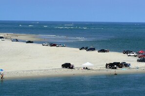 A beach with vehicles parked on the sand and a tent set up.