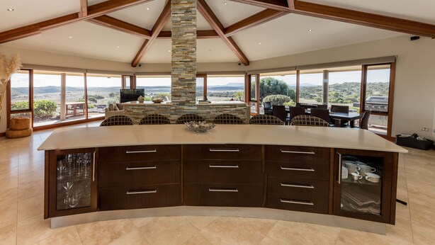 A spacious kitchen with a large island, stone pillar, and a view of the landscape. - Almonta Park Lodge (Coffin Bay)