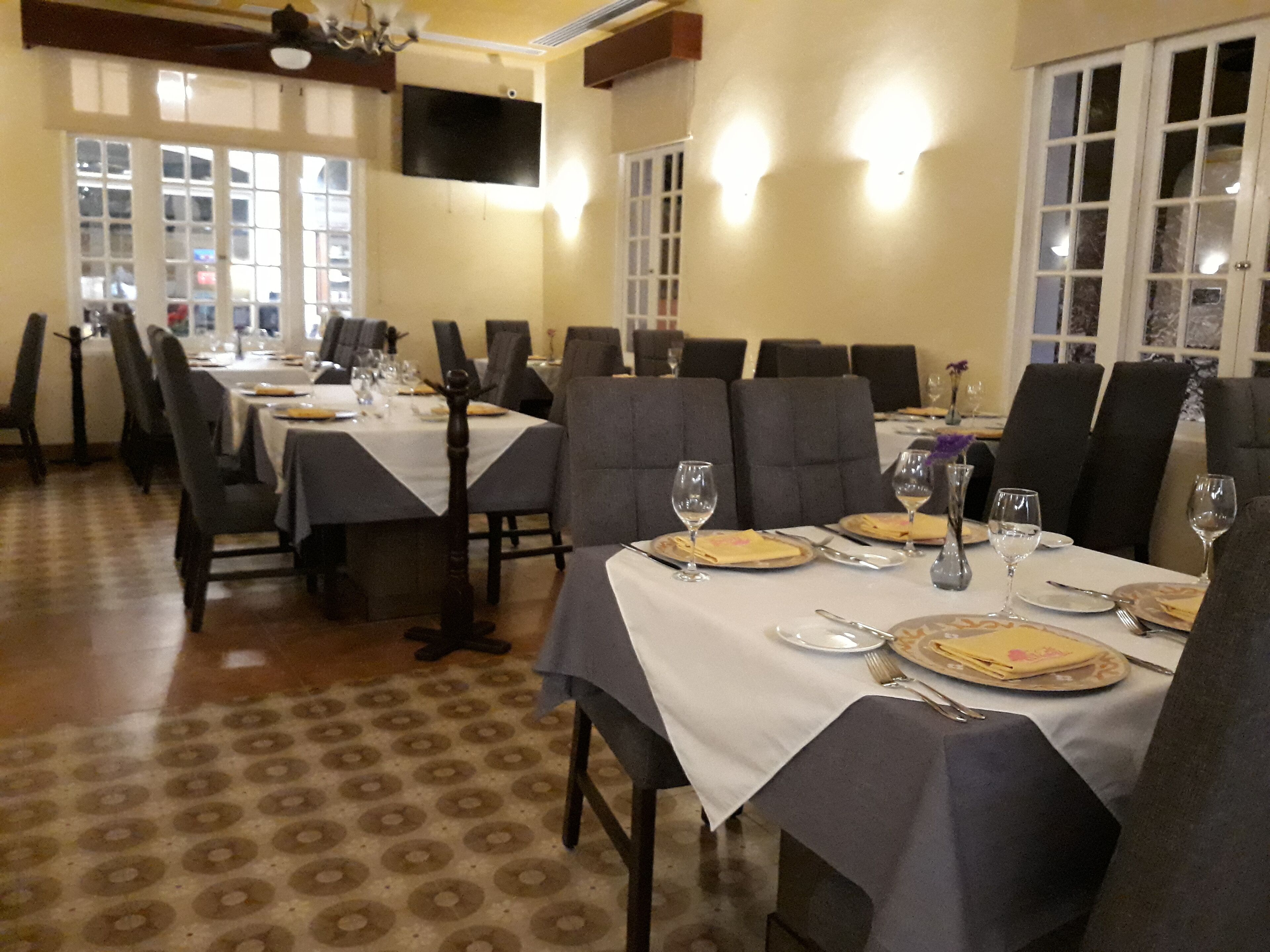 A dining area with tables set for a meal, chairs, and a television mounted on the wall.