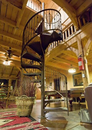 A spiral staircase in a wooden interior with a fire extinguisher on the wall. - Butch Cassidy Country Ranch Stay near Capitol Reef (Teasdale)