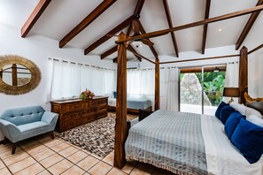 Ein Schlafzimmer mit einem großen Bett, einer Holzkommode, einem blauen Sessel und einem Spiegel an der Wand.