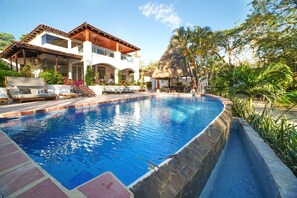 Ein Swimmingpool mit Liegestühlen und einer überdachten Sitzgruppe.