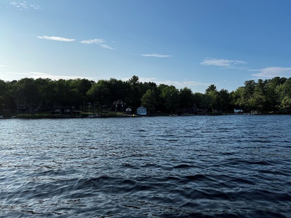 Un lac aux eaux calmes, bordé d’arbres et entouré de maisons.