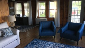 Una sala de estar acogedora con un sofá blanco, sillones azules y un tapete estampado.