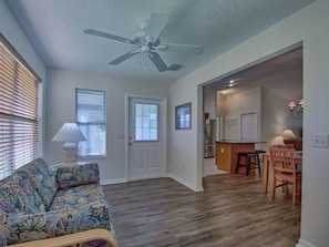 A living room with a ceiling fan, a sofa, and a dining area with chairs and a table.