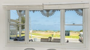 A room with a large window overlooking a golf course and the ocean. - Doc's Cottage Lancelin - Ocean Views - Pet Friendly. (Lancelin)