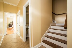A hallway with a wooden staircase and a door leading to a bathroom.
