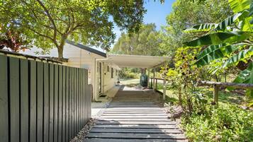 A covered walkway leading to a building with a 'No Parking' sign, surrounded by lush greenery and trees.